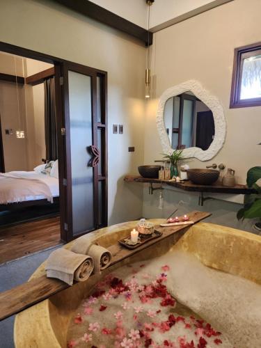 a bathroom with a bath tub with flowers in it at Prana Siargao Resort in General Luna