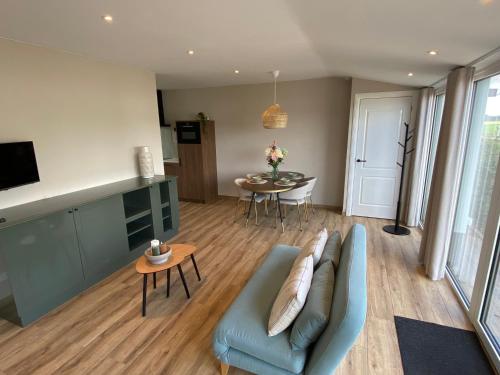 Una sala de estar con un sofá azul y una mesa. en Appartement Oisterwijk, en Moergestel