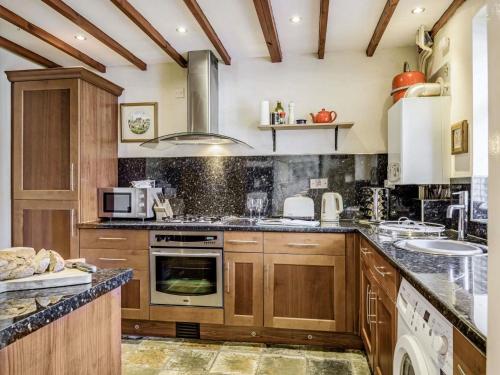 a kitchen with wooden cabinets and a stove top oven at 2 Bed in Llangattock BN228 in Llangattock