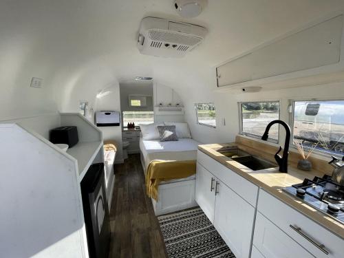 a small kitchen with a bed and a sink in a caravan at Rustic Charm meets Modern Luxury: Cozy Airstream in Grand Junction, Colorado in Grand Junction