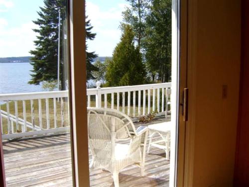 a door open to a deck with a table and chair at Cozy Lakeside Vacation Rental near St David, Maine in Lavertue