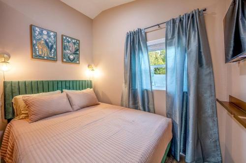 a bedroom with a bed and a window with blue curtains at Off-Grid Tiny House with Fire Pit and Countryside Views in Tennessee in Parrottsville
