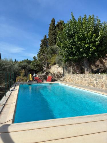 a swimming pool with blue water in a yard at Mas des quatre cyprès in Spéracèdes