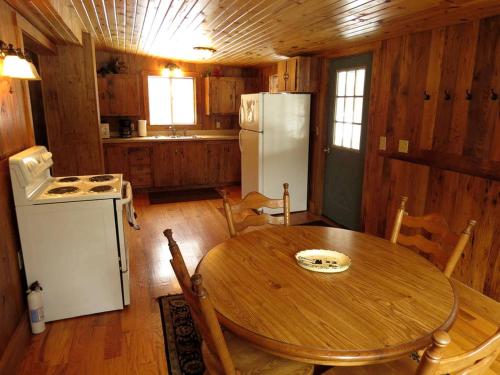 une cuisine avec une table en bois et un réfrigérateur blanc dans l'établissement Secluded Rental Cabin with Hot Tub near Deep Creek Lake in West Virginia, à Cranesville