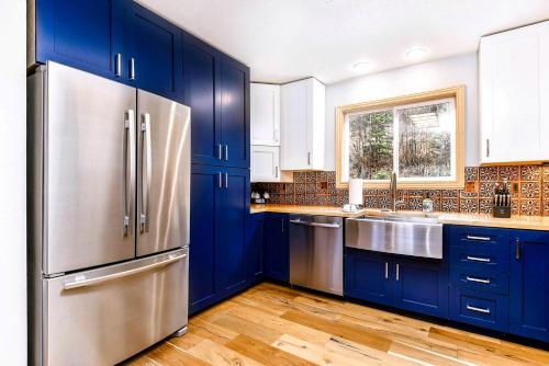 a kitchen with blue cabinets and a stainless steel refrigerator at High-altitude Hideaway: Large Rental on Schweitzer Mountain with Views and Hot Tub in Bronx
