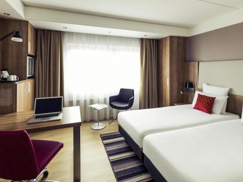 a hotel room with two beds and a laptop on a desk at Mercure Hotel Nijmegen Centre in Nijmegen