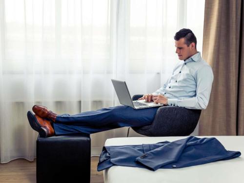 a man sitting on a chair with a laptop at Mercure Hotel Nijmegen Centre in Nijmegen