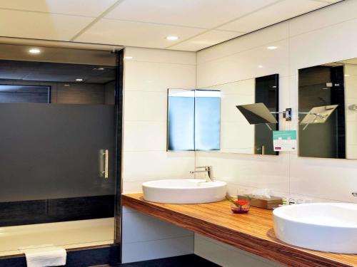 a bathroom with a sink and a mirror at Mercure Hotel Nijmegen Centre in Nijmegen