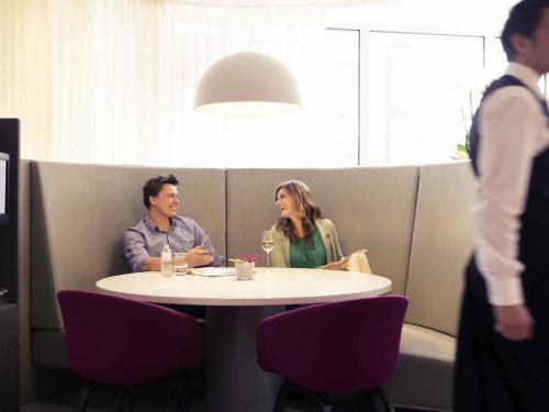 a man and woman sitting at a table in a restaurant at Mercure Hotel Nijmegen Centre in Nijmegen
