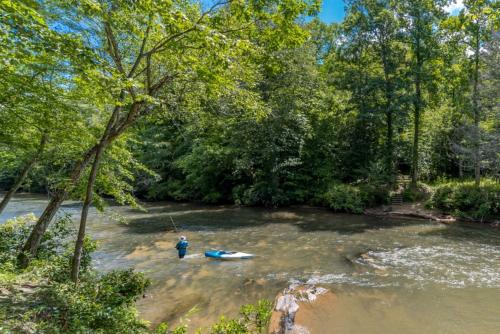 a man is standing in a river with a kayak at Fantastic Cabin with Fire Pit, Hot-tub and Fireplace in Sautee Nacoochee, Georgia in Aerial