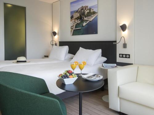 a hotel room with a bed and a couch and a table at Mercure Ajaccio in Ajaccio