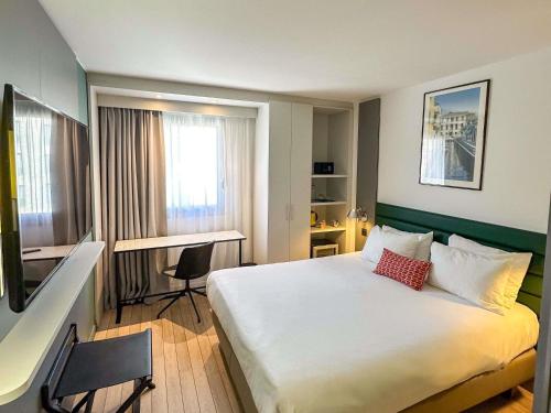 a hotel room with a large bed and a desk at Mercure Ajaccio in Ajaccio
