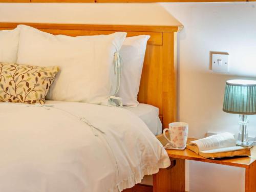 a bedroom with a bed and a table with a lamp and a book at 1 Bed in Kidwelly 43406 in Kidwelly