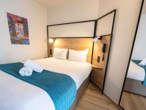 a bedroom with a large bed with a blue blanket at ibis Avignon Centre Pont De L'Europe in Avignon