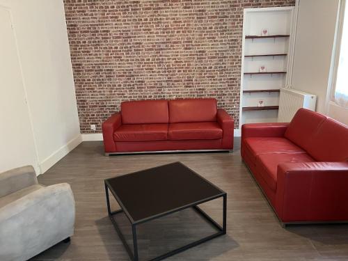 a living room with two red couches and a table at Hébergements le Camp d'Auneau - Aunay Bien in Auneau