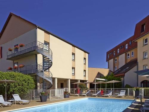 a hotel with a swimming pool in front of a building at ibis Beaune Centre in Beaune