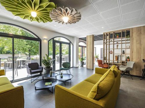 a lobby with a yellow couch and chairs and windows at ibis Beaune Centre in Beaune