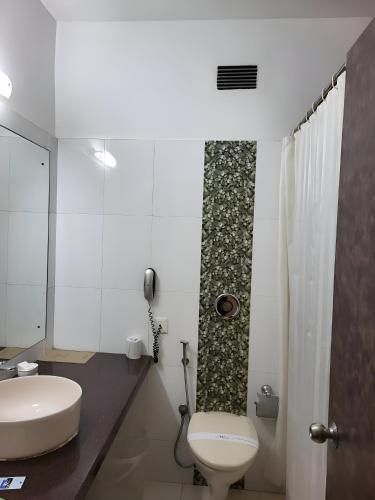 a bathroom with a white toilet and a sink at The New Marrion in Bhubaneshwar