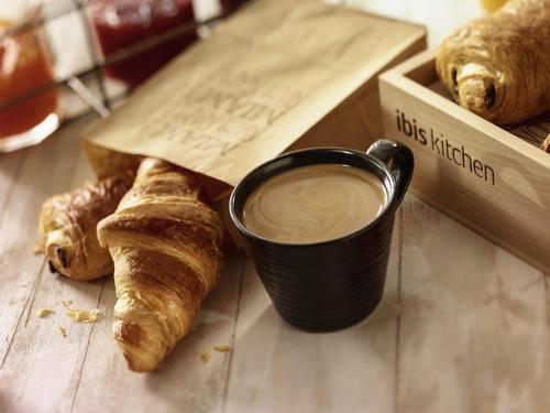 a cup of coffee next to a box of croissants at ibis Beaune Centre in Beaune