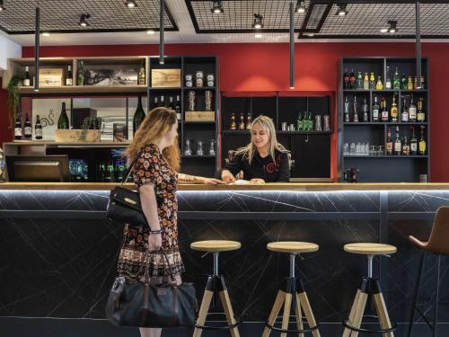 two women standing at a bar at ibis Beaune Centre in Beaune
