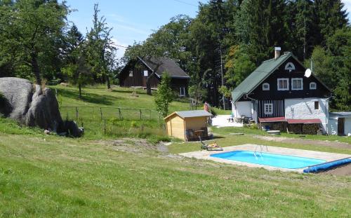 a house and a pool in a field with a house at Na Sluneční Pohádková chaloupka ve Sladké díře in Příchovice