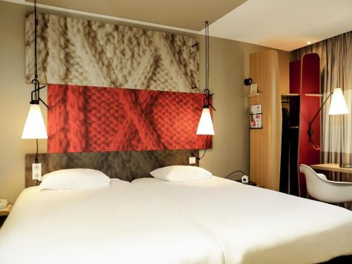 a hotel room with two beds and a red wall at ibis Besançon Centre Ville in Besançon
