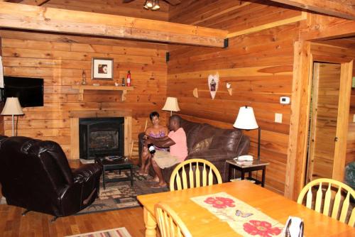 a man and woman sitting on a couch in a living room at Rustic Cabin Rental in the Wilderness near Beckley, West Virginia in Hico