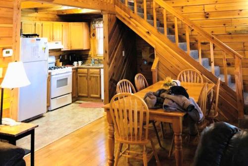 a kitchen with a table with chairs and a staircase at Rustic Cabin Rental in the Wilderness near Beckley, West Virginia in Hico