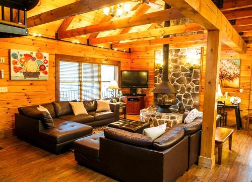 a living room with leather furniture and a stone wall at Charming Log Cabin Rental for a Group Getaway in Shenandoah, Virginia in Grove Hill