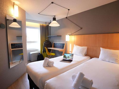 a hotel room with two beds with a laptop on it at ibis Colmar Centre in Colmar