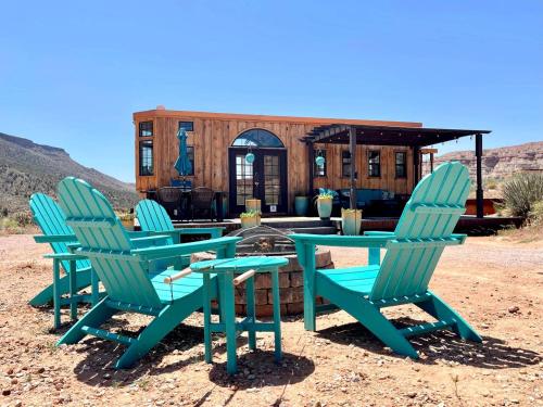 three chairs and a table in front of a house at The Ark Tiny House near Zion National Park, Utah in Virgin