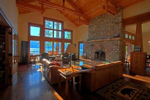 a living room with couches and a stone fireplace at Lakeside Vacation Rental with Stunning Views and Spacious Interior on Flathead Lake, Montana in Finley Point