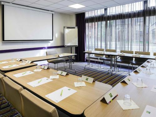 une salle de conférence avec des tables, des chaises et un écran dans l'établissement ibis Styles Lille Centre Gare Beffroi, à Lille