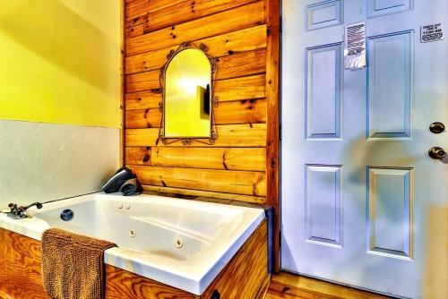 ein Badezimmer mit einer weißen Badewanne neben einer Tür in der Unterkunft Cozy Creekside Cabin Rental near Cherokee, North Carolina in Cherokee