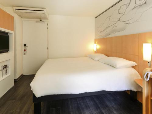 a bedroom with a large white bed and a tv at ibis Lyon Part Dieu Les Halles in Lyon