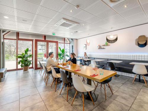 two people sitting at a table in a restaurant at ibis Lyon Part Dieu Les Halles in Lyon