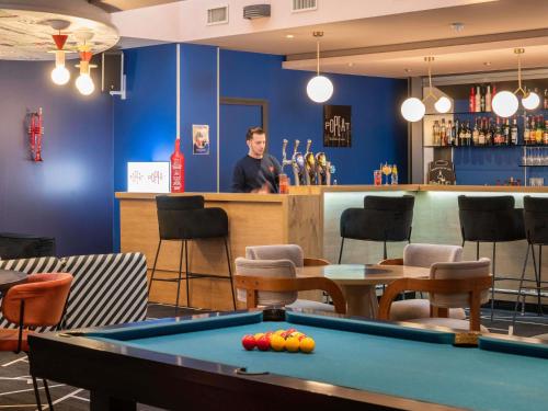 a man standing at a bar with a pool table at ibis Lyon Part Dieu Les Halles in Lyon
