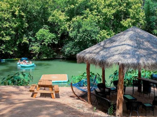 a hut and a raft in a river with people in a boat at Rest and Relax in Texas in this Great Safari Tent Getaway in Cibolo in Marion