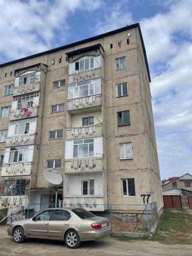 un coche aparcado delante de un edificio alto en Little Comfort Home, en Karakol