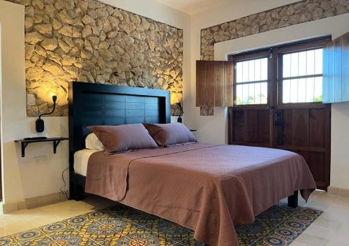 a bedroom with a large bed and a stone wall at Casa Michela512 ,Piscina y Mérida centro in Mérida