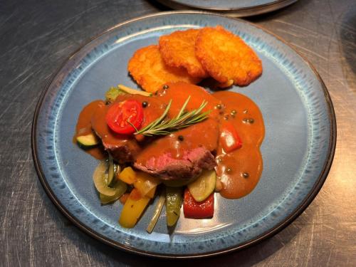 a plate of food with meat and vegetables on a table at Andi's Skihotel in Obertauern