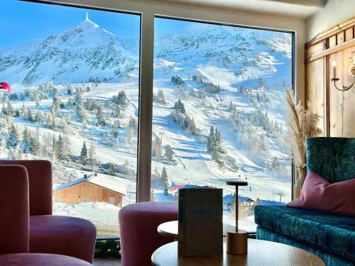 a room with a view of a snowy mountain through a window at Andi's Skihotel in Obertauern