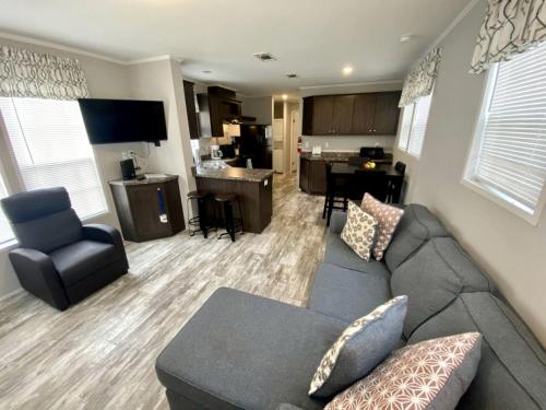 a living room with a gray couch and a kitchen at Picturesque Cottage with Fire Pit in Dunnellon, Florida in Dunnellon