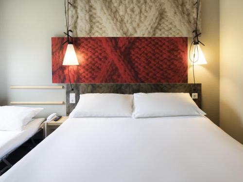 a bedroom with a white bed and a red wall at ibis Dijon Gare in Dijon