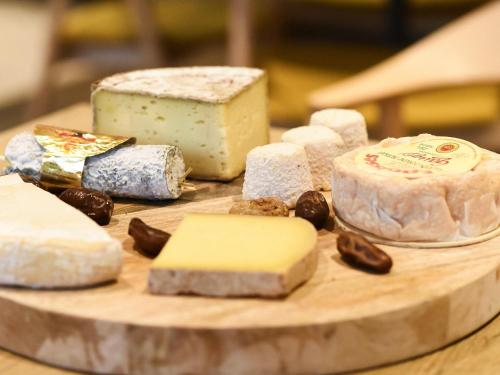 a bunch of different types of cheese on a cutting board at ibis Dijon Gare in Dijon