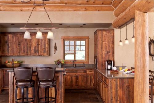 a kitchen with wooden cabinets and a counter with bar stools at Scenic Creekside Lodge with Decks and Madison River Access near Yellowstone, Ennis Montana in Grahams Place