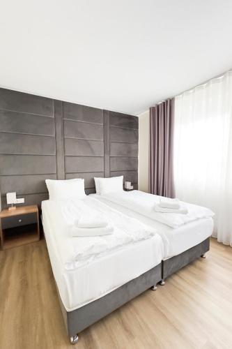 a large white bed in a bedroom with a wooden floor at O&O Hotel Oberursel Zentrum in Oberursel