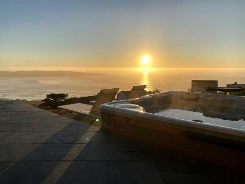 eine Badewanne auf einer Terrasse mit Blick auf den Sonnenuntergang in der Unterkunft Sky House Boutique Seaside Retreat With Cinema Near Dillon Beach in Dillon Beach