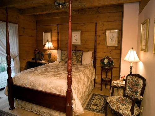ein Schlafzimmer mit Himmelbett und Sessel in der Unterkunft Family Cabin Vacation Getaway with Waterfall Views in Northwest Arkansas in Ponca