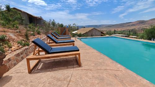 two lounge chairs sitting next to a swimming pool at Akagera Park Inn in Akagera